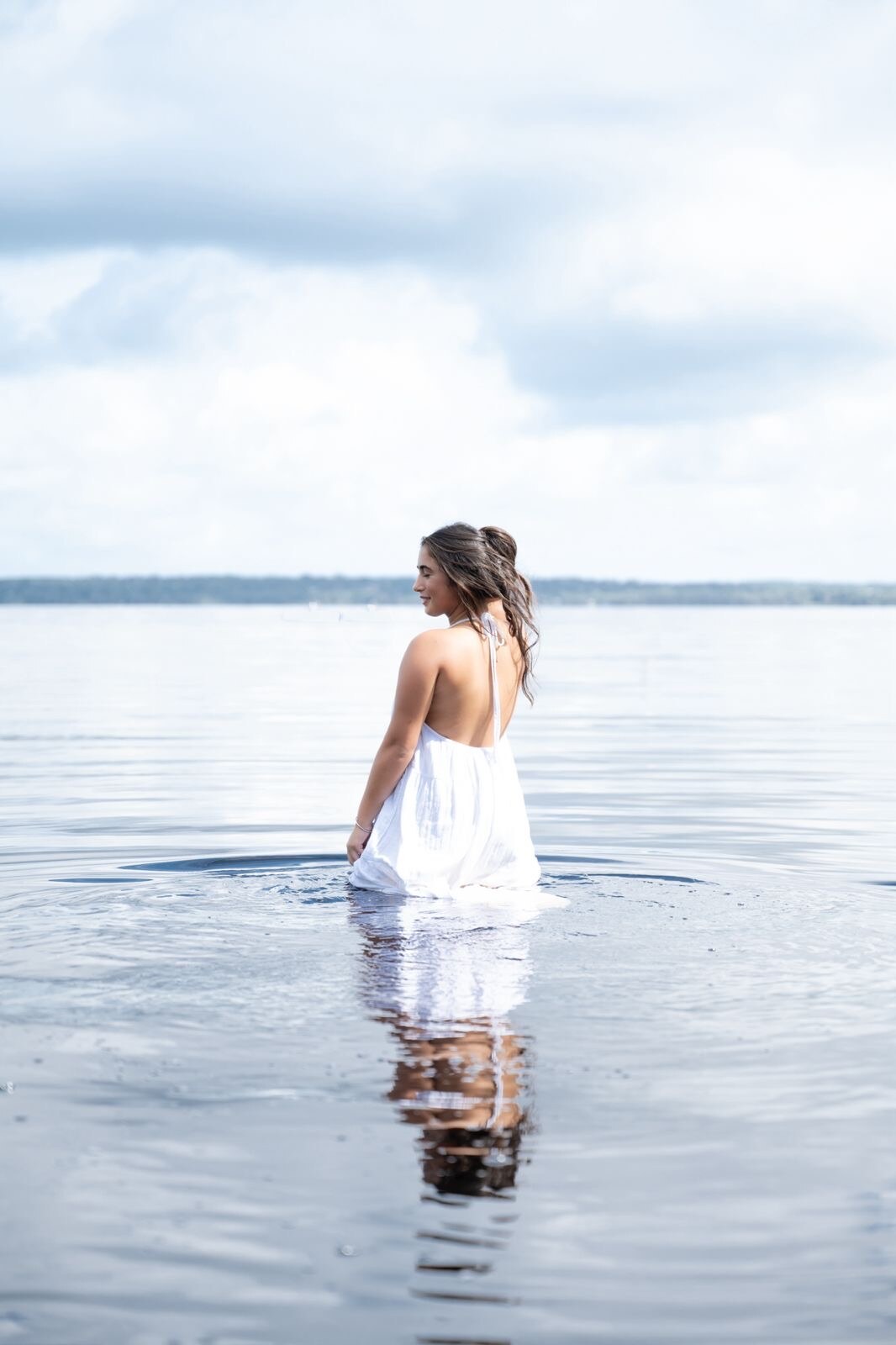 Editorial portrait of a woman standing in a calm lake