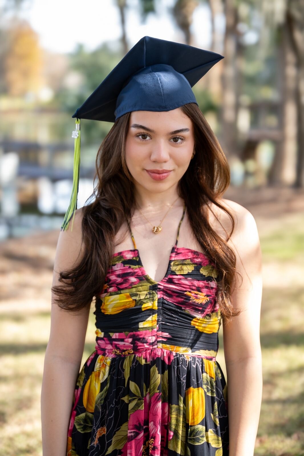 Graduate in a floral dress and cap celebrating outdoors