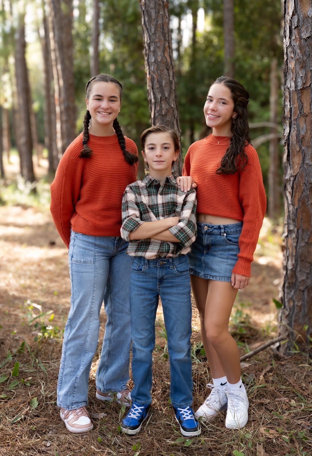 Three siblings together in a pine forest